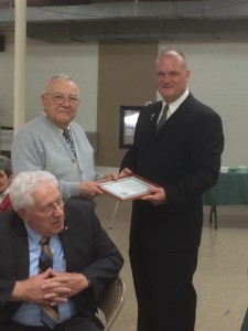 PM Bob receiving an award and PM Ron sitting.